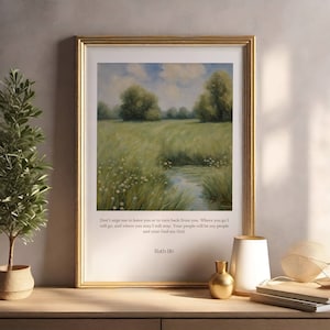 Op de afbeelding: Een ingelijst druk met een schilderij van een groen veld met een klein beekje dat er doorheen loopt. Het schilderij is omgeven door een gouden lijst. De print bevat een citaat uit de Bijbel: "Dring me niet om je te verlaten of om terug te keren van je. Waar je heen gaat, ga ik heen, en waar je blijft, blijf ik. Je volk zal mijn volk zijn en je God mijn God." - Ruth 1:16