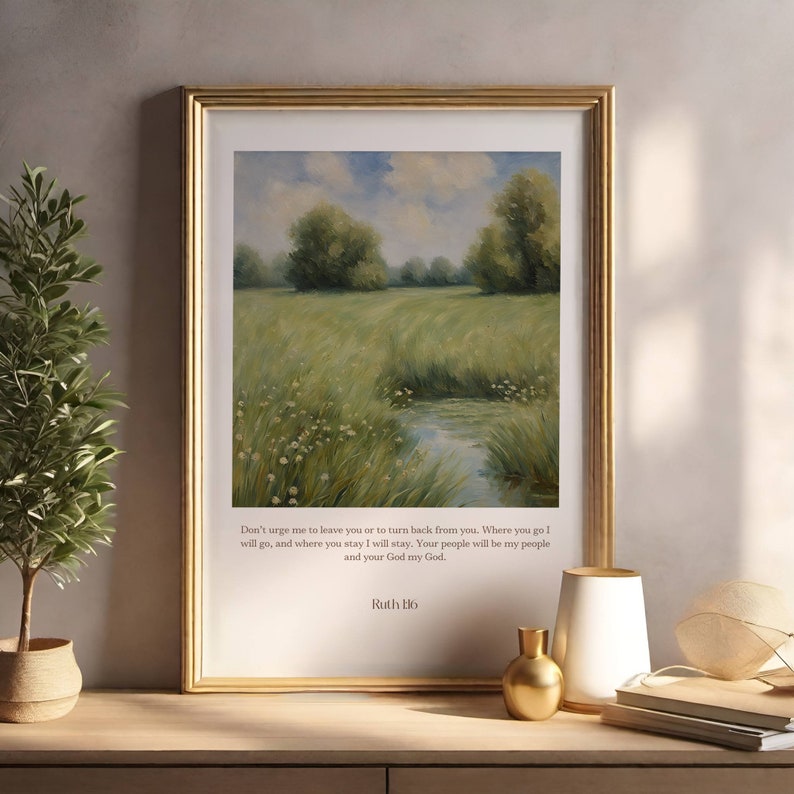 Op de afbeelding: Een ingelijst druk met een schilderij van een groen veld met een klein beekje dat er doorheen loopt. Het schilderij is omgeven door een gouden lijst. De print bevat een citaat uit de Bijbel: "Dring me niet om je te verlaten of om terug te keren van je. Waar je heen gaat, ga ik heen, en waar je blijft, blijf ik. Je volk zal mijn volk zijn en je God mijn God." - Ruth 1:16