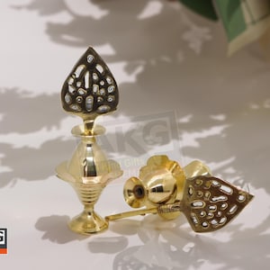 May include: Two ornate, gold-colored metal perfume bottles. One is upright, featuring a decorative, openwork top. The other lies on its side, with a similar design. The bottles have a classic, elegant aesthetic.