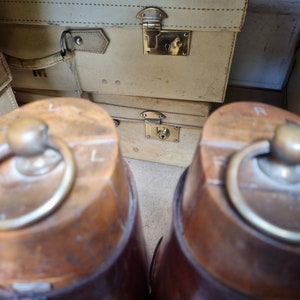 May include: Two brown leather boots with brass buckles. The boots have a worn, vintage look and are made of a sturdy material.
