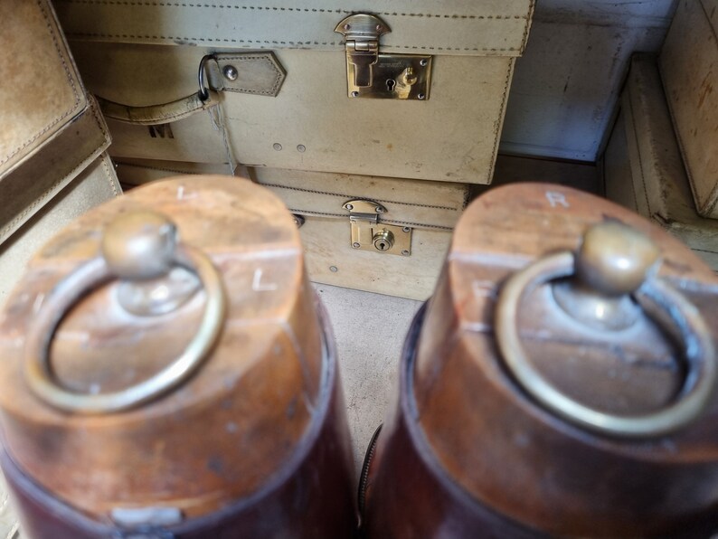 May include: Two brown leather boots with brass buckles. The boots have a worn, vintage look and are made of a sturdy material.