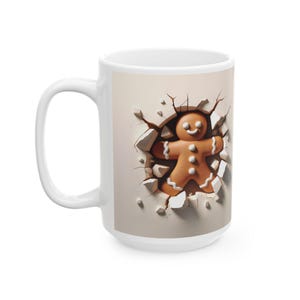 May include: White ceramic mug featuring a 3D illustration of a gingerbread man breaking through a wall. The gingerbread man is brown with white icing details. The mug is a standard size for coffee or tea.