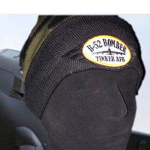 May include: Black and green knit beanie with a yellow and white patch that reads "B-52 BOMBER TINKER AFB".