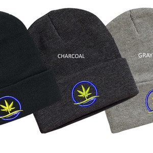 Puede incluir: Tres gorros de punto en negro, carb&oacute;n y gris con un dise&ntilde;o de hoja de marihuana bordada en azul y amarillo. Los gorros est&aacute;n doblados y se muestran sobre un fondo blanco.