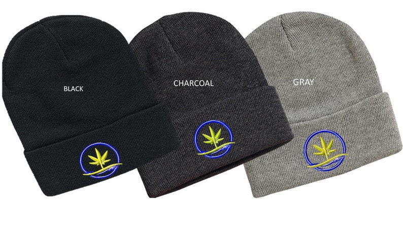 Puede incluir: Tres gorros de punto en negro, carb&oacute;n y gris con un dise&ntilde;o de hoja de marihuana bordada en azul y amarillo. Los gorros est&aacute;n doblados y se muestran sobre un fondo blanco.