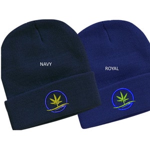 Puede incluir: Dos gorros de punto con un logotipo de hoja de marihuana verde en un c&iacute;rculo azul. El gorro de la izquierda es azul marino y dice "NAVY". El gorro de la derecha es azul real y dice "ROYAL".