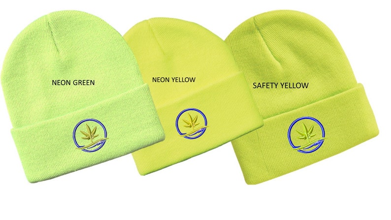 Puede incluir: Tres gorros de punto en diferentes tonos de amarillo: verde ne&oacute;n, amarillo ne&oacute;n y amarillo de seguridad. Cada gorro tiene un logotipo bordado circular con una hoja verde estilizada y una ola azul.