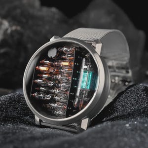 K&ouml;nnte beinhalten: Eine runde Armbanduhr mit silberfarbenem Metall-Mesh-Armband und rundem Geh&auml;use. Das Zifferblatt zeigt eine offene elektronische Anzeige mit mehreren kleinen Glas-Vakuumr&ouml;hren und einer gr&ouml;&szlig;eren leuchtend blauen R&ouml;hre, mit dem Schriftzug NIWA.