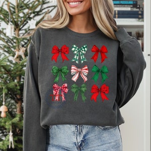May include: A dark gray sweatshirt with a festive design of nine red and green bows. The bows are arranged in a grid pattern on the front of the sweatshirt.
