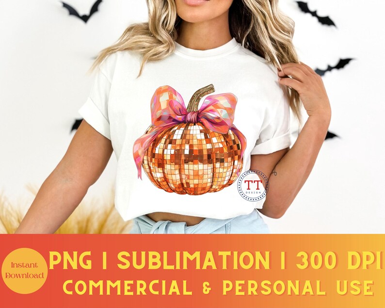 K&ouml;nnte beinhalten: Ein wei&szlig;es T-Shirt mit einem Motiv einer Disco-K&uuml;rbis mit einer rosa Schleife. Der K&uuml;rbis ist orange und goldfarben mit einem glitzernden Finish. Der Text "TT Design" befindet sich in der unteren rechten Ecke des Bildes.