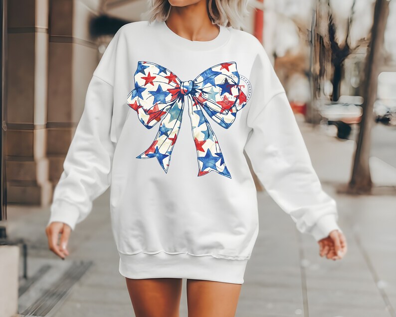 Pu&ograve; includere: Felpa bianca con un grande fiocco rosso, bianco e blu con stelle stampate.