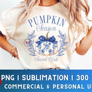 May include: A white t-shirt with a blue and white pumpkin design. The text "Pumpkin Season Social Club" is printed on the shirt.