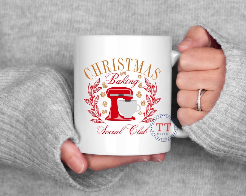 May include: White ceramic mug with a red and gold design. The design features a stand mixer, a wreath of holly, and the text "Christmas Baking Social Club".