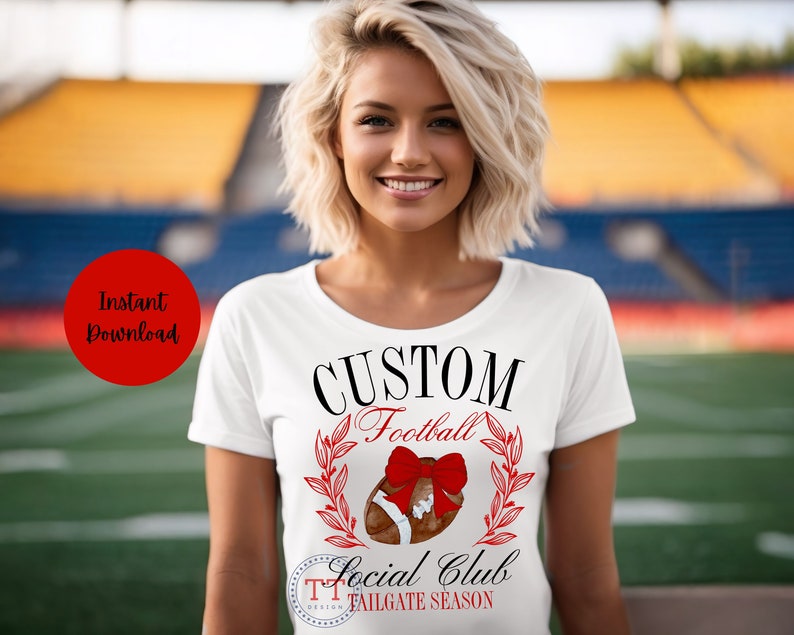 May include: White t-shirt with black text that reads "CUSTOM Football Social Club TAILGATE SEASON". A red bow is on top of a brown football with green leaves around it.
