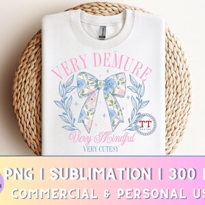 Peut inclure: Un sweat-shirt blanc avec un n&oelig;ud rose et bleu et le texte "VERY DEMURE Very Mindful VERY CUTESY" imprim&eacute; sur le devant.