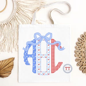 May include: White tote bag featuring a patriotic design. The design includes the letters "ABC" in red, white, and blue patterns, with a blue bow at the top. The letter "A" is blue with white stars, "B" has a pattern of American flags, and "C" is red gingham.