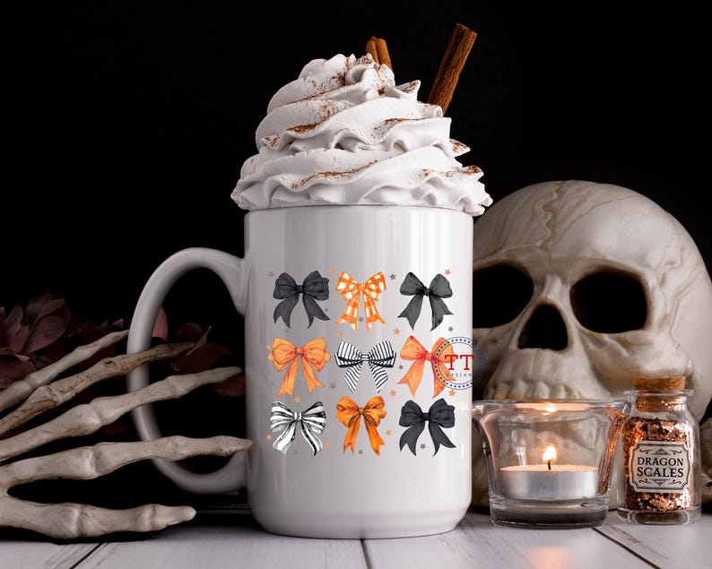 Pu&ograve; includere: Una tazza in ceramica bianca con un motivo a fiocco nero e arancione. La tazza &egrave; piena di panna montata e un bastoncino di cannella. La tazza &egrave; appoggiata su una superficie bianca con un teschio e un barattolo di pozione.