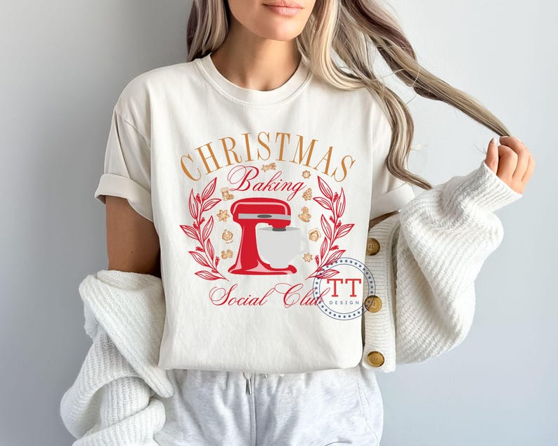May include: White t-shirt with a red and gold design featuring a kitchen mixer and the text "Christmas Baking Social Club".