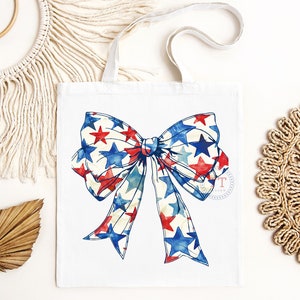 Pu&ograve; includere: Una borsa di tela bianca con un fiocco rosso, bianco e blu con stelle stampate.