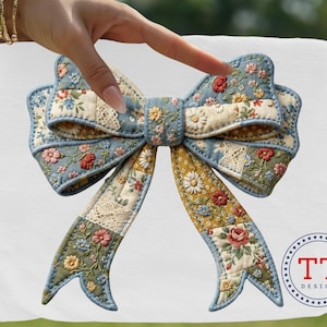 Peut inclure: Un nœud patchwork avec des motifs floraux dans les tons de bleu, jaune et rouge. Le nœud est en tissu et présente un élément de dentelle décorative. Le nœud est tenu par une main.