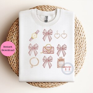 May include: A white sweatshirt with a design of pink bows, a gold watch, a gold chain necklace, a gold purse, a bottle of perfume, and gold earrings. The design is in a watercolor style.