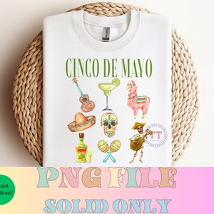 Pu&ograve; includere: Una maglietta bianca con il testo "Cinco de Mayo" in lettere verdi. La maglietta presenta una variet&agrave; di illustrazioni colorate, tra cui una chitarra, una margarita, un lama, un sombrero, uno scheletro, maracas e uno scheletro che suona la chitarra. Il testo "TT Design" &egrave; incluso anche in un cerchio.
