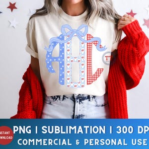 May include: A cream-colored t-shirt featuring a patriotic monogram design with the letters "AHC". The "A" is blue with white stars, the "H" has a pattern of red, white, and blue flags, and the "C" is red gingham. A blue bow tops the design.