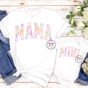 Puede incluir: Camisas blancas con las palabras "Mama" y "Mini" escritas en colores pastel con un patr&oacute;n de caramelos Peeps pastel.
