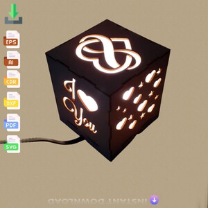 May include: A black wooden cube night light with a cut-out design of an infinity symbol, hearts, and stars. The light illuminates the design, creating a warm glow. The words "I love you" are also cut out on the side of the cube.