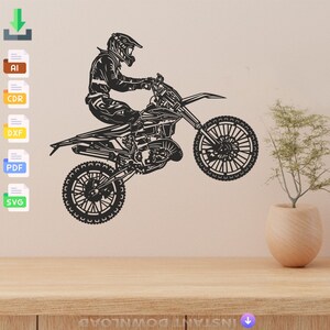 Puede incluir: Una silueta en blanco y negro de un piloto de motocross realizando una acrobacia en una moto de cross. El piloto lleva casco y gafas, y la moto está en el aire con la rueda delantera levantada.