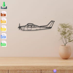 May include: Black metal airplane wall art. The airplane is a side profile with a propeller and a detailed outline. The art is mounted on a light beige wall above a wooden table. A small plant in a beige pot is on the table.