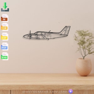 Może przedstawiać: Czarna metalowa grafika ścienna przedstawiająca samolot. Samolot jest w profilu z szczegółowymi liniami, w tym śmigłem, oknami i ogonem. Grafika jest zamontowana na jasnobeżowej ścianie nad drewnianym stołem.