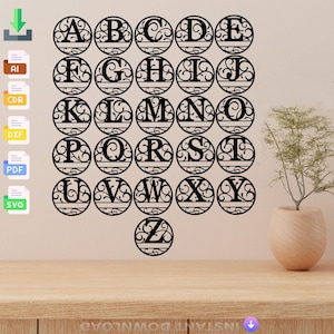 May include: Black laser-cut wooden alphabet letters A to Z, each within a decorative circular frame. The letters are displayed on a light brown wooden surface against a beige wall. A small plant in a beige pot is on the right.