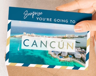 May include: A postcard with a photo of Cancun, Mexico, with the text "Surprise, You're Going To... Cancun." The postcard has a blue and white striped border with a gold accent. The postcard is held in a person's hand.