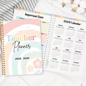 Op de afbeelding: Een spiraalgebonden lerarenplanner met een pastelkleurig regenboogontwerp en de tekst "Teacher Planner 2025-2026". De open planner toont een kalender voor 2025 en een pagina met de titel "Important Date".