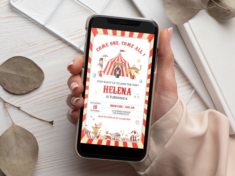 Op de afbeelding: Een smartphonescherm met een verjaardagsuitnodiging in circusthema met rood- en cr&egrave;mekleurige gestreepte randen. De tekst luidt: COME ONE, COME ALL!, STEP RIGHT UP TO JOIN THE FUN!, HELENA IS TURNING 6, 18 OKTOBER, SHOWTIME: 16:00 UUR.