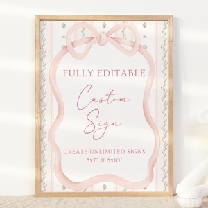 May include: A framed sign with a light wood frame. The sign has a pink bow and a pink wavy border. The text on the sign reads "FULLY EDITABLE Custom Sign CREATE UNLIMITED SIGNS 5x7 & 8x10". The background has a floral pattern.