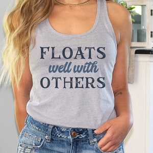 May include: A gray tank top with the text "FLOATS well with OTHERS" in blue lettering.