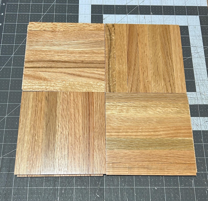 Puede incluir: Cuatro piezas cuadradas de suelo de madera en varios tonos de marr&oacute;n. La veta de la madera es visible en cada pieza.