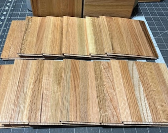 May include: A stack of wooden floorboards in various shades of brown, with a few showing a lighter, almost white, grain pattern.