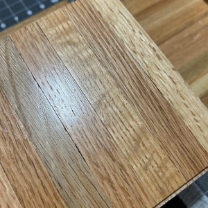 Puede incluir: Primer plano de una superficie de madera hecha de m&uacute;ltiples tiras de madera. La madera tiene un patr&oacute;n de veta natural y un color marr&oacute;n claro.