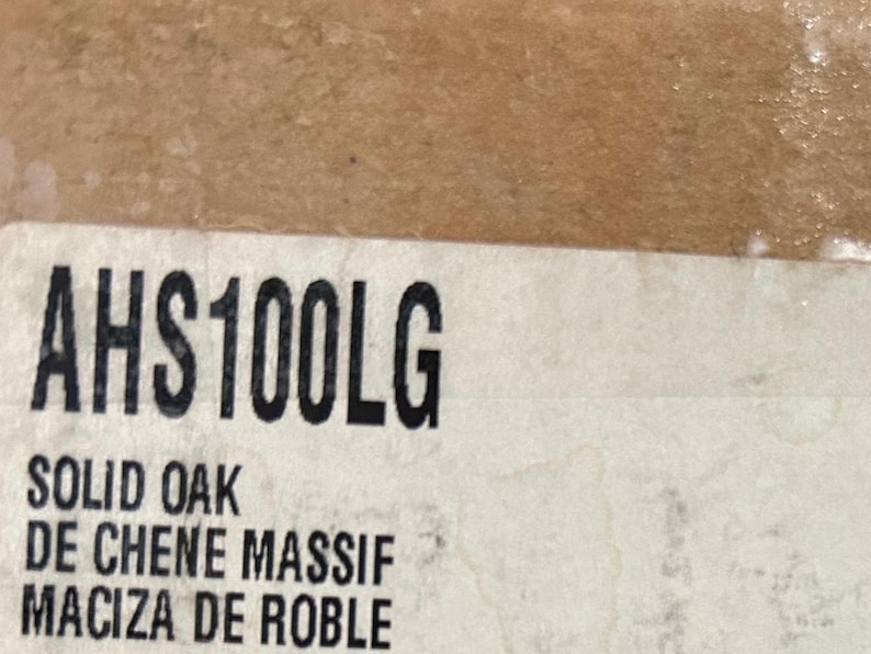 Puede incluir: Primer plano de una etiqueta blanca con texto negro. La etiqueta dice "AHS100LG" y "SOLID OAK DE CHENE MASSIF MACIZA DE ROBLE".