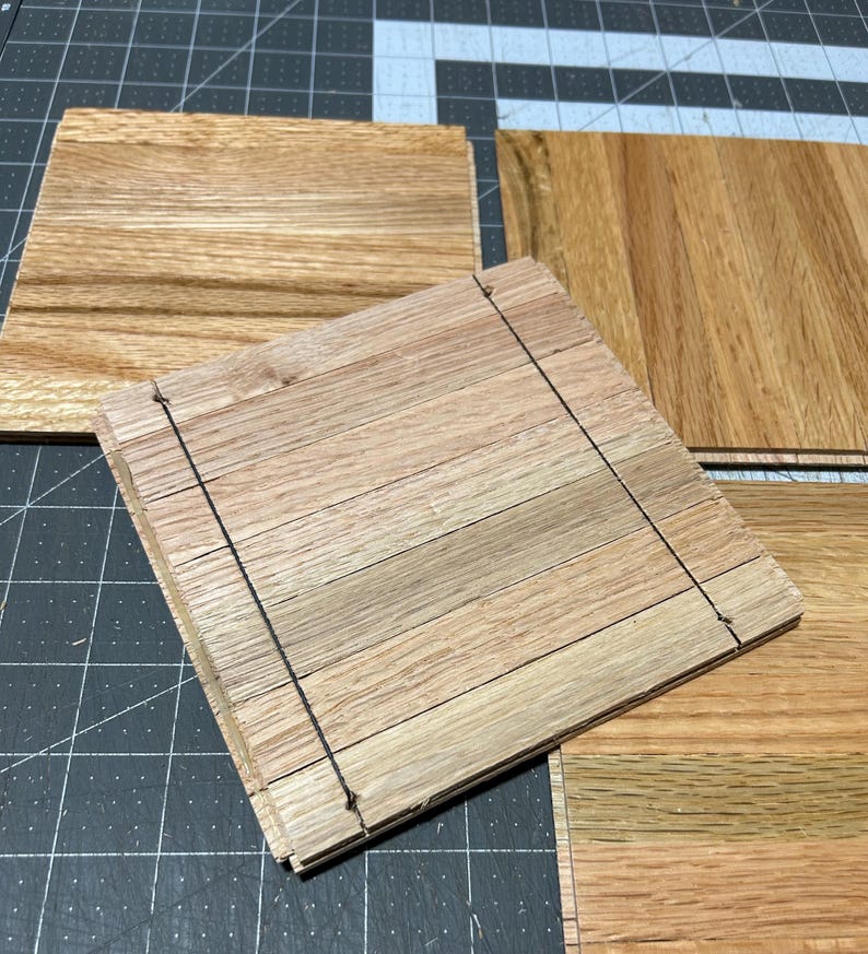Puede incluir: Cuatro piezas de suelo de madera sin terminar, cada una con un patr&oacute;n de veta de madera natural. Las piezas est&aacute;n apiladas una encima de la otra, con la pieza superior ligeramente desplazada de las dem&aacute;s. La madera es de color marr&oacute;n claro.