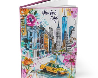 May include: A hardcover journal featuring a colorful watercolor illustration of New York City. The cover displays a yellow taxi cab, buildings, and the text "New York City" in script. Floral accents in pink and orange add a decorative touch.