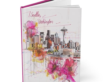 May include: A pink and white journal with a watercolor illustration of the Seattle skyline, including the Space Needle, and pink flowers. The text "I Seattle, Washington" is written on the front cover.