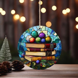 May include: Round Christmas ornament featuring a stack of books with colorful ornaments on top. The ornament has a stained glass design with blue, green, purple, and red accents. A string is attached for hanging.