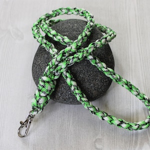 May include: A green, black, and white braided lanyard with a silver swivel clasp.