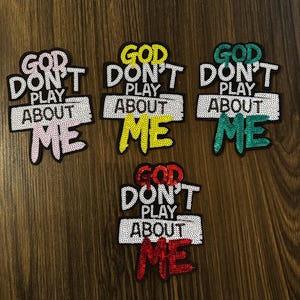 May include: Embroidered patches with the text "GOD DON'T PLAY ABOUT ME" in various colors: pink, yellow, green, and red. The patches have a sequined border and are designed for clothing or accessories.