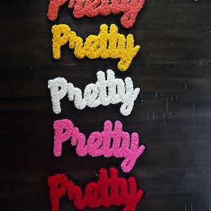 May include: A white ceramic mug with a black handle and the text "But First, Coffee" in a bold, black font. The mug is set against a blurred background, suggesting a cozy setting.