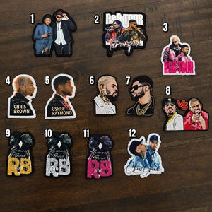 May include: A collection of twelve embroidered patches featuring graphic illustrations of musical artists Chris Brown and Usher. The designs include portraits, tour-themed imagery, and text such as R&B TOUR, The Merger, and Raymond and RB.